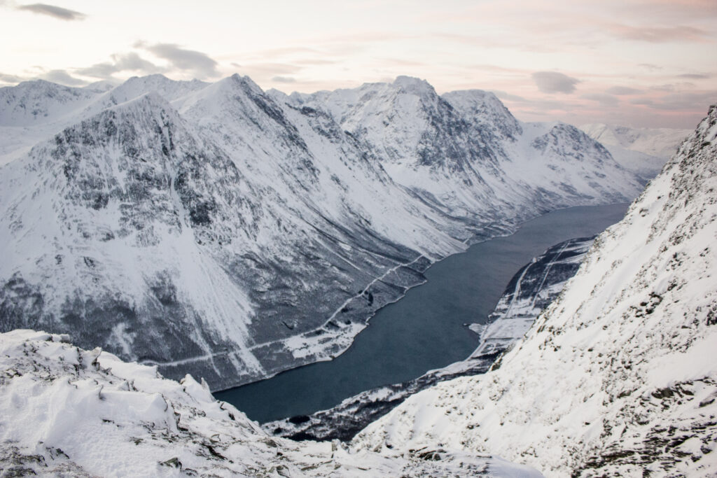 Winterlandschaft in den Lyngenalpen mit verschneiten Bergen und Fjorden.