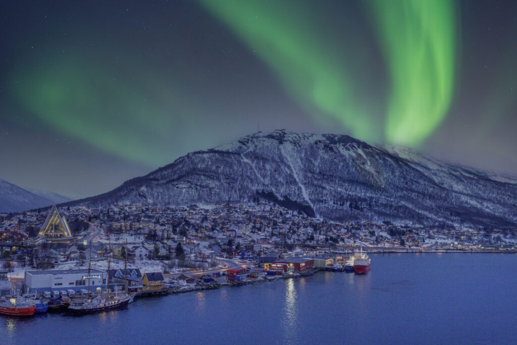 Nordlichter leuchten über Tromsø, Norwegen, mit winterlicher Landschaft.