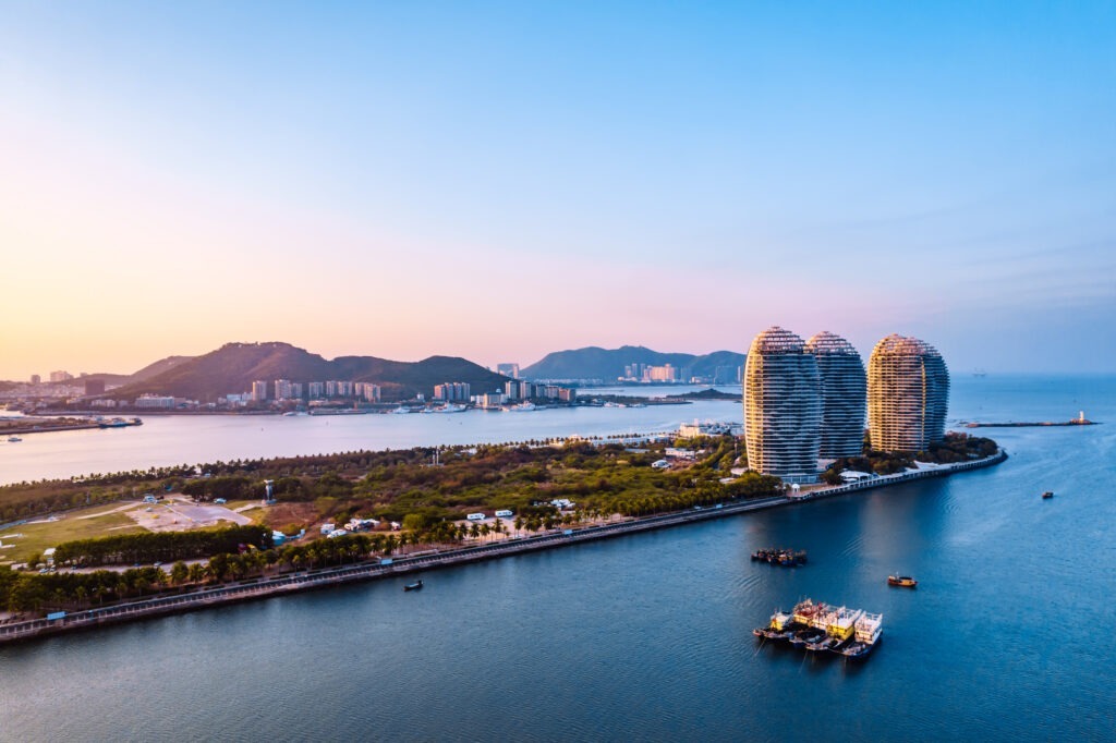 Blick auf die Küstenlinie der Sanya Bay mit Phoenix Island, Hainan, China.