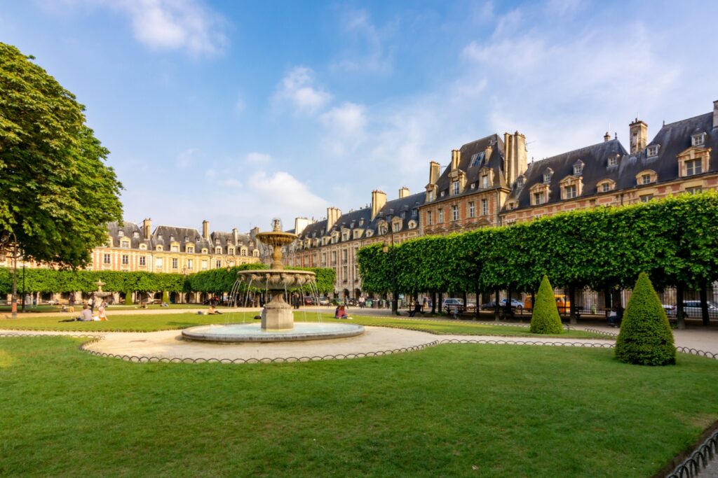 Der Place des Vosges, ein eleganter Platz mit symmetrischen roten Backsteinfassaden, Arkaden und einer grünen Parkanlage in der Mitte.