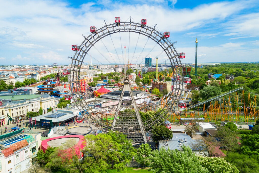 Der Praterpark in Wien mit dem berühmten Riesenrad, grünen Bäumen und einer belebten Atmosphäre an einem sonnigen Tag.