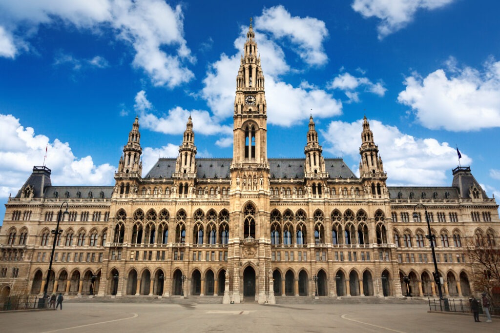 Das Wiener Rathaus, ein imposantes neugotisches Gebäude mit markanten Türmen und kunstvoller Fassade, festlich beleuchtet in der Abenddämmerung.