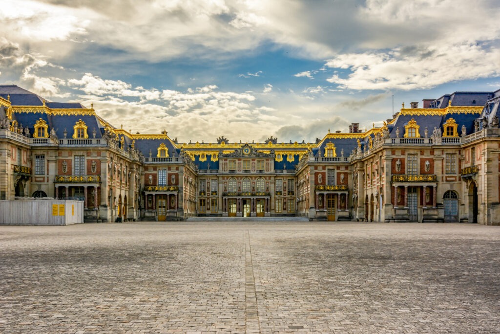 Schloss Versailles bei Sonnenuntergang, mit seiner prächtigen Fassade, ist ein Symbol königlicher Eleganz.