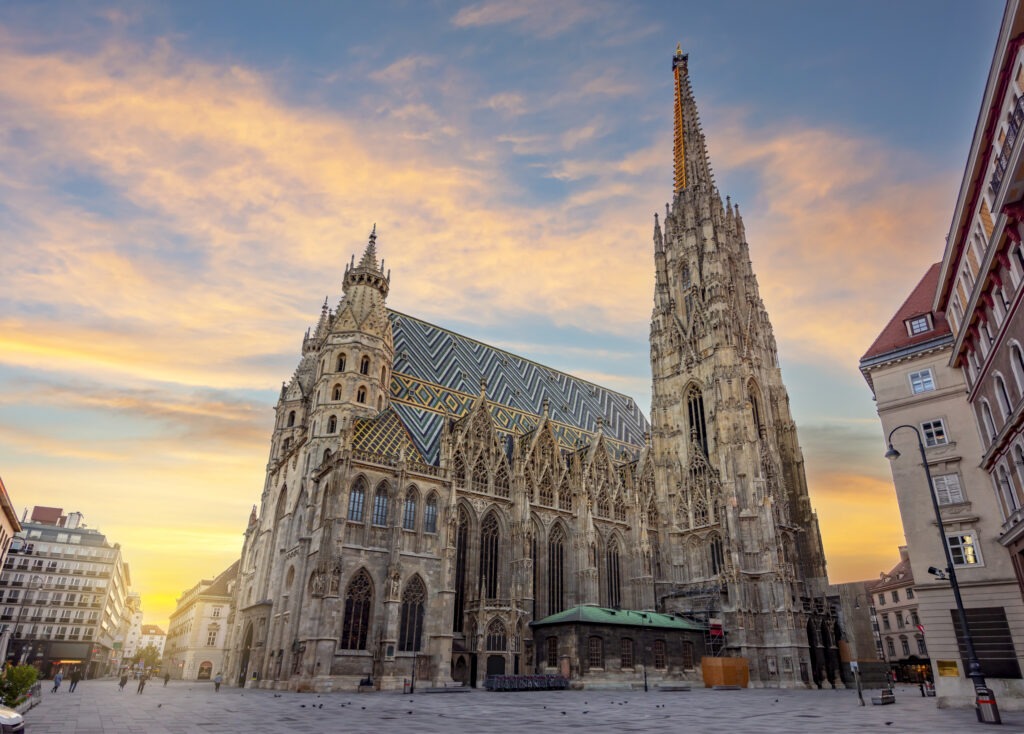 Der Stephansdom am Stephansplatz in Wien bei Sonnenaufgang, mit seiner markanten gotischen Architektur und dem farbenfrohen Ziegeldach.