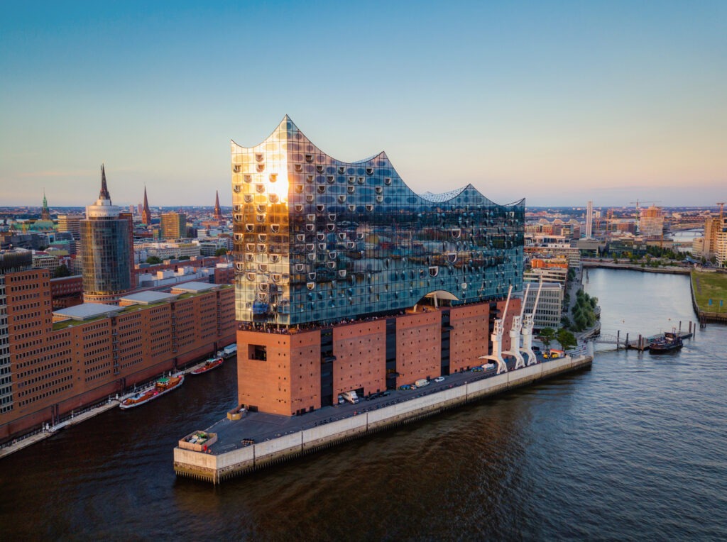 Elbphilharmonie in Hamburg bei Sonnenuntergang, mit reflektierendem Glasdach und Blick auf den Hafen.