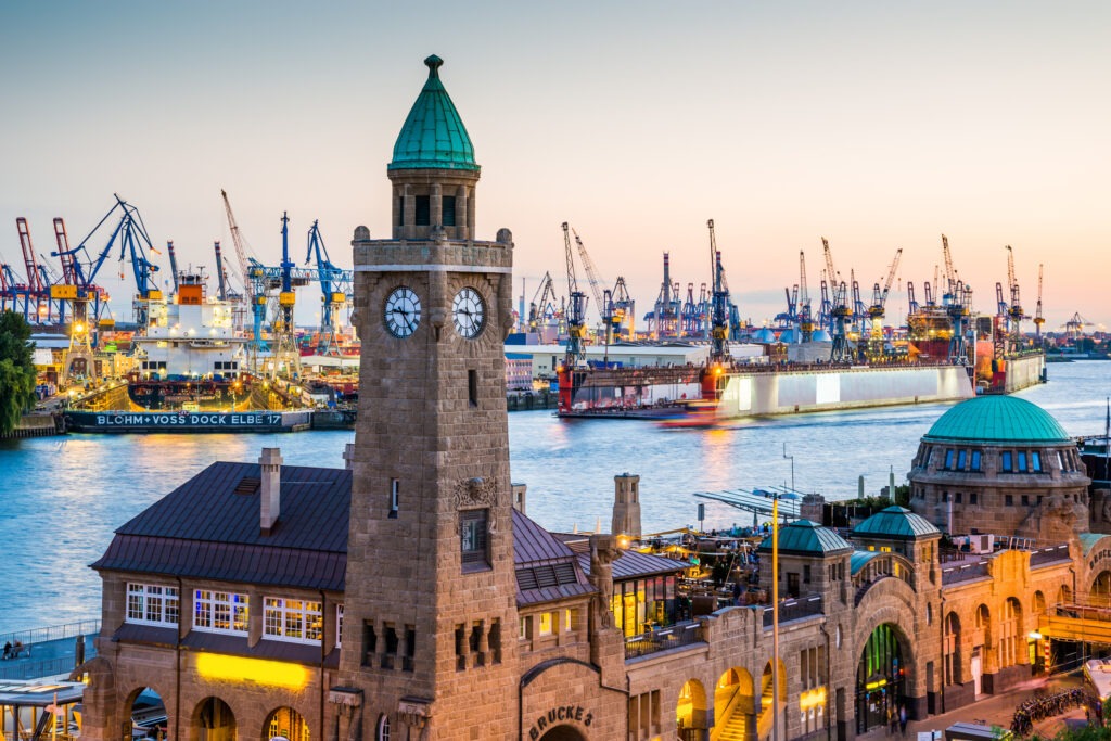 Blick auf den Hamburger Hafen mit historischer Architektur, im Vordergrund die Alster mit Spiegelungen im Wasser.