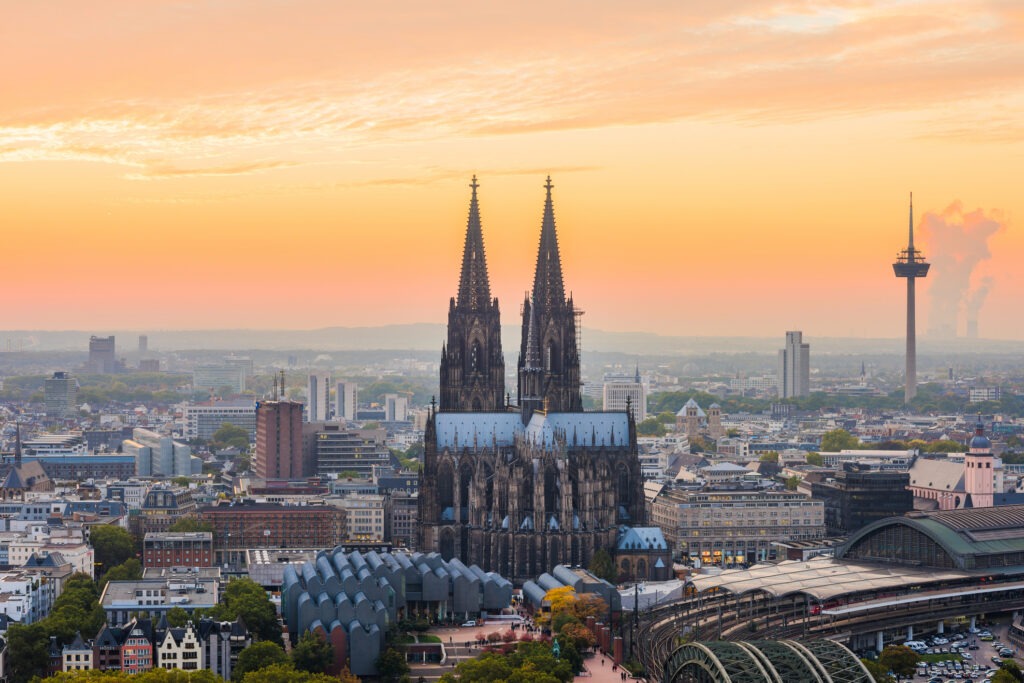 Kölner Dom bei Nacht, imposant beleuchtet mit beeindruckender gotischer Architektur und Spiegelung auf dem nassen Pflaster.