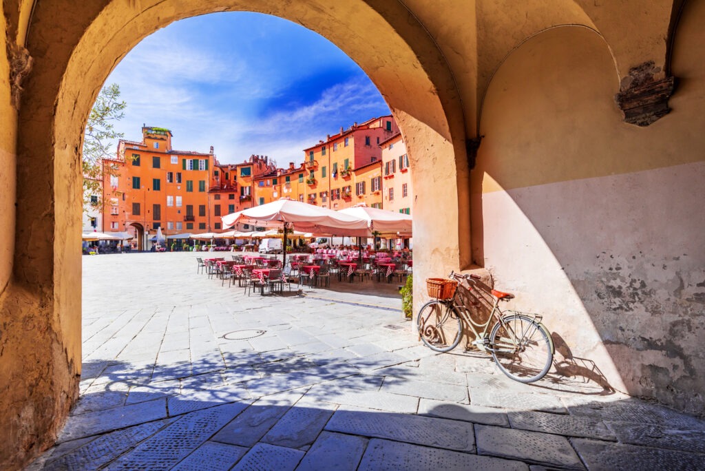 Piazza dell’Anfiteatro in Lucca mit farbenfrohen historischen Gebäuden und mediterranem Flair in der Toskana.