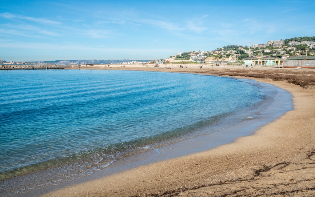 Malerischer Blick auf den Prado-Strand in Marseille, Frankreich, an einem sonnigen Tag mit blauem Meer und entspannter Strandatmosphäre.