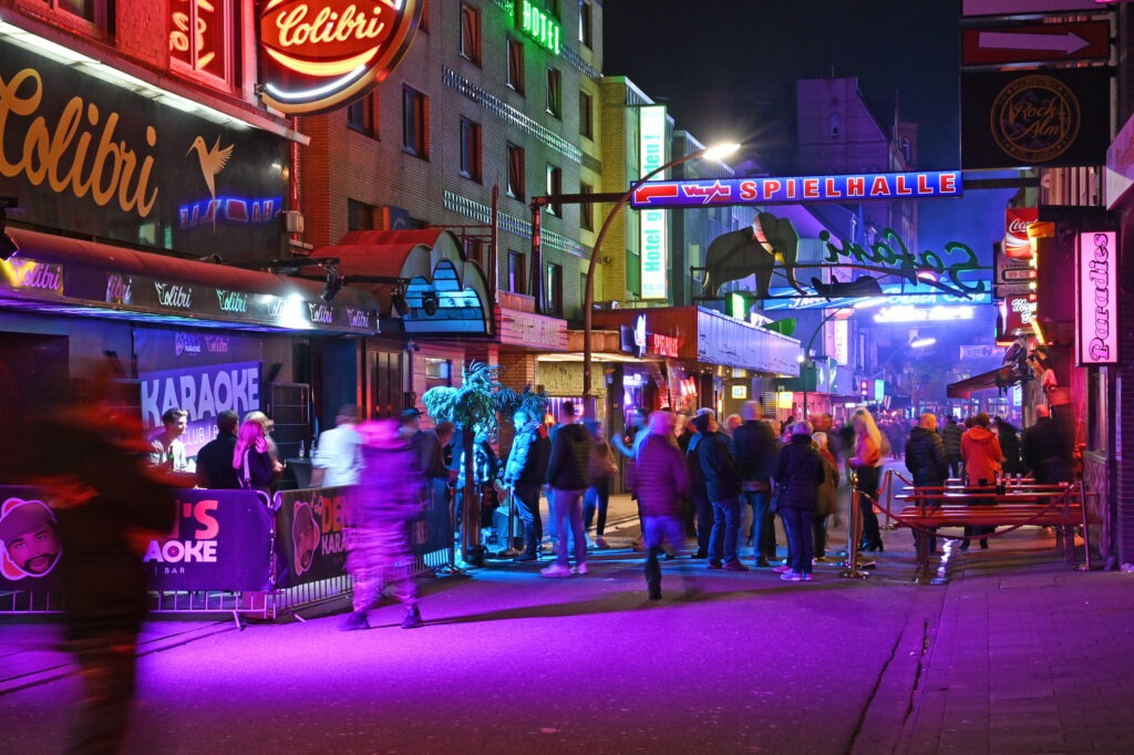 Die berühmte Reeperbahn bei Nacht, mit leuchtenden Neonlichtern und belebter Straße.