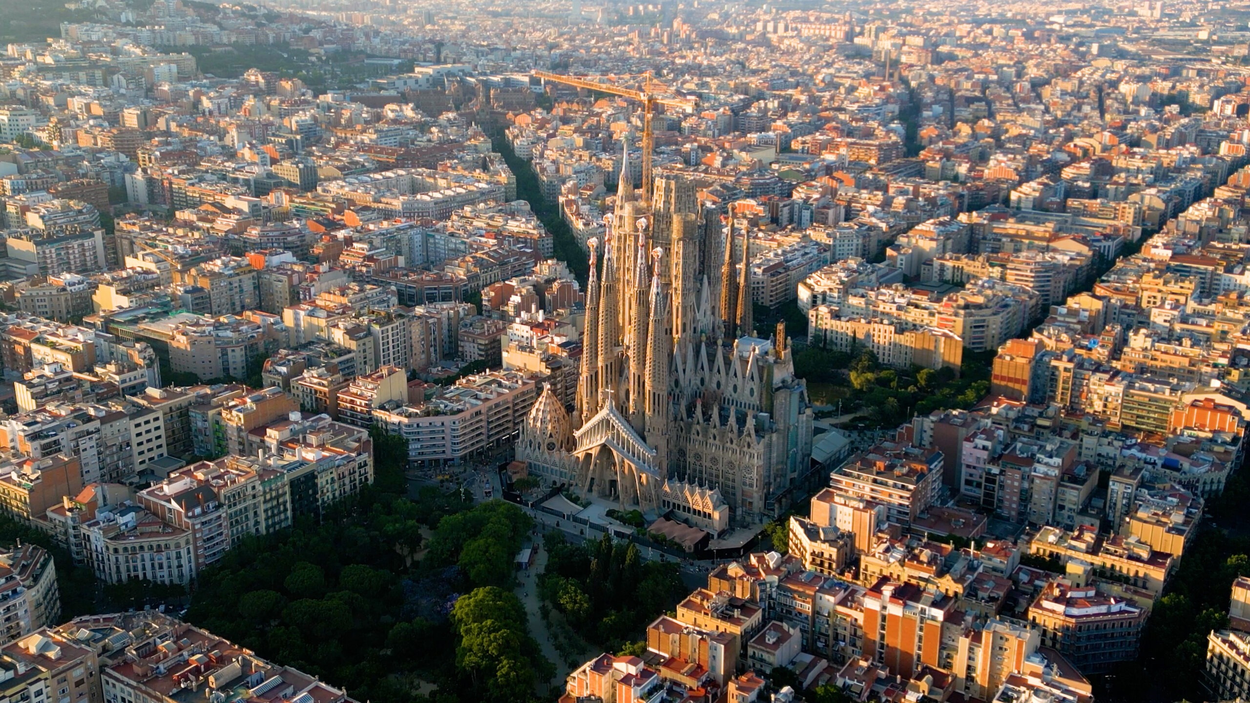 Luftaufnahme des Stadtviertels Eixample in Barcelona mit der berühmten Basilika Sagrada Família im Zentrum.